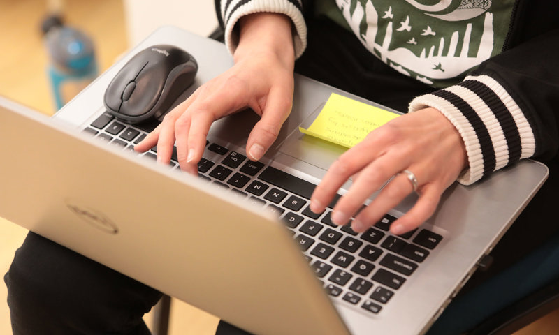 A person with a laptop on their lap typing on the keyboard 