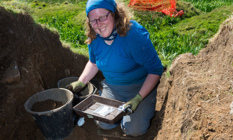 A woman with a headscarf on taking part in an archaeology dig