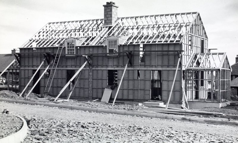 A 1950s house during construction. The timber framework is visible, and wooden beams are holding up the walls.